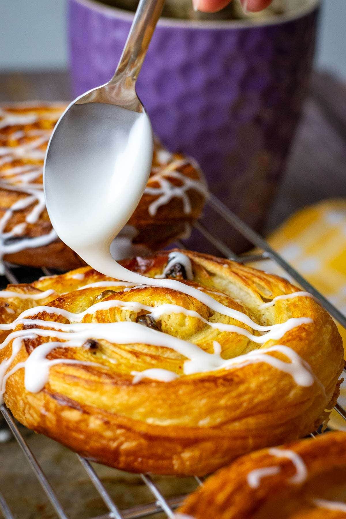 Drizzling lemon icing on top of sourdough pain aux raisins.