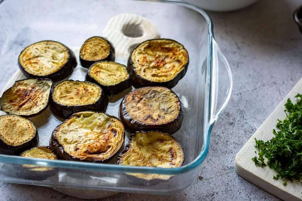 Aubergine slices arranged on the base of an overproof dish.