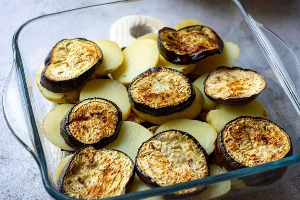 Another layer of aubergine slices on top of potatoes.
