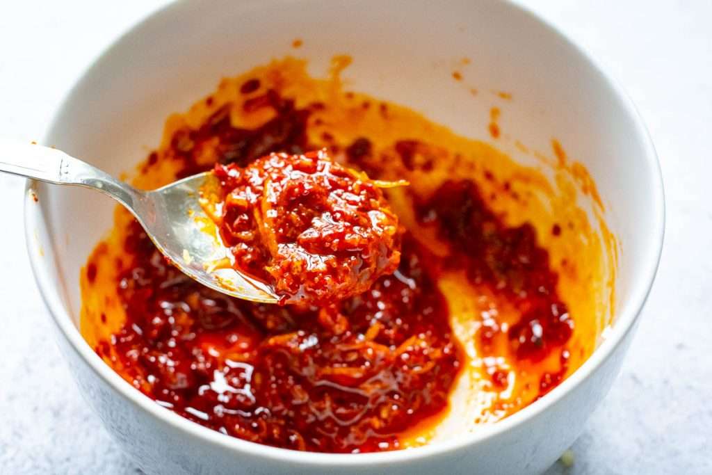 Mixed ingredients for a harissa marinade in a small white bowl.