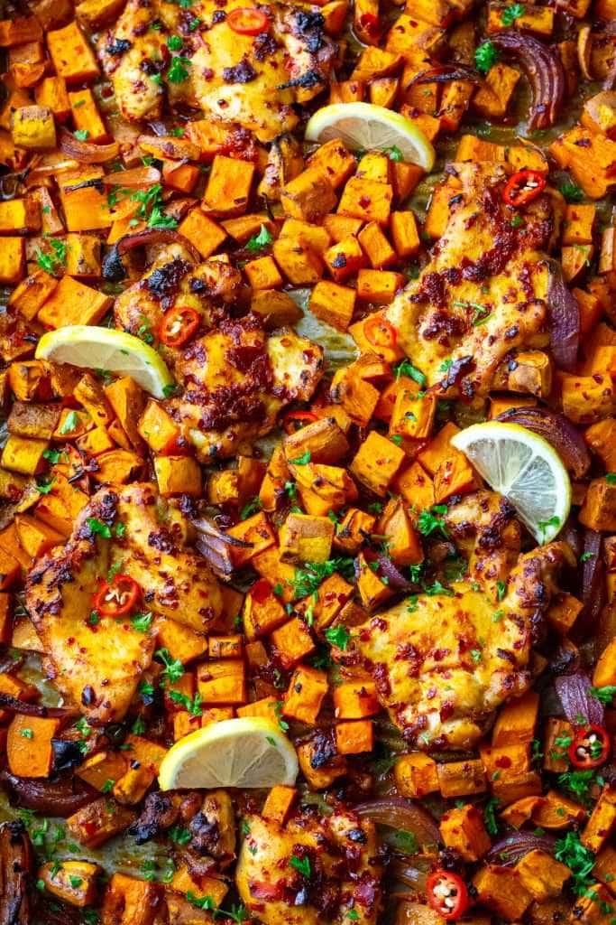 Harissa Chicken Thigh Tray bake after baking garnished with lemon slices.