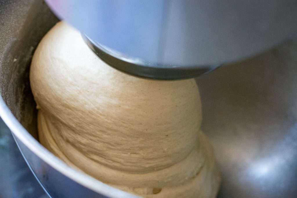 Sourdough in a stand mixer fitted with a dough hook attachment.