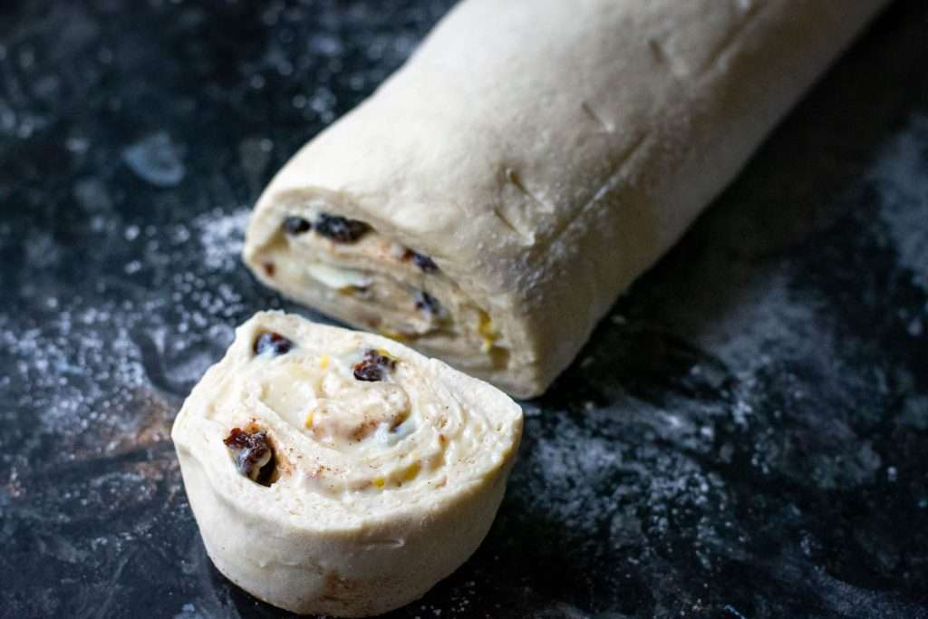 The Sourdough pain aux raisins log being cut cross wise.