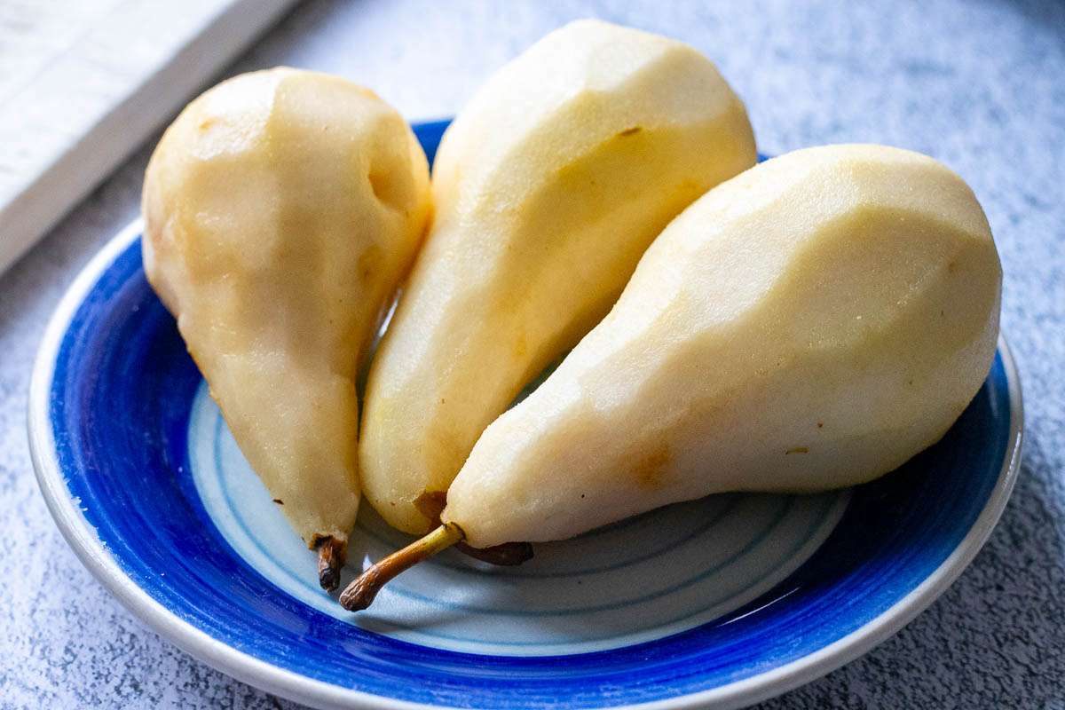 Peeled pears on a small blue plate.