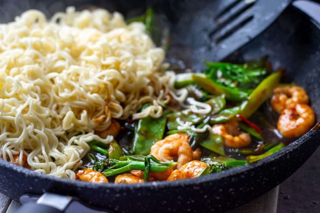 Cooked noodles added to the teriyaki prawn sir fry pan.