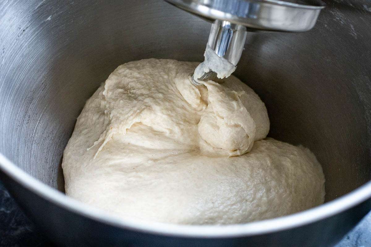 Sourdough warpping around a dough hook attachment in a stand mixer bowl.