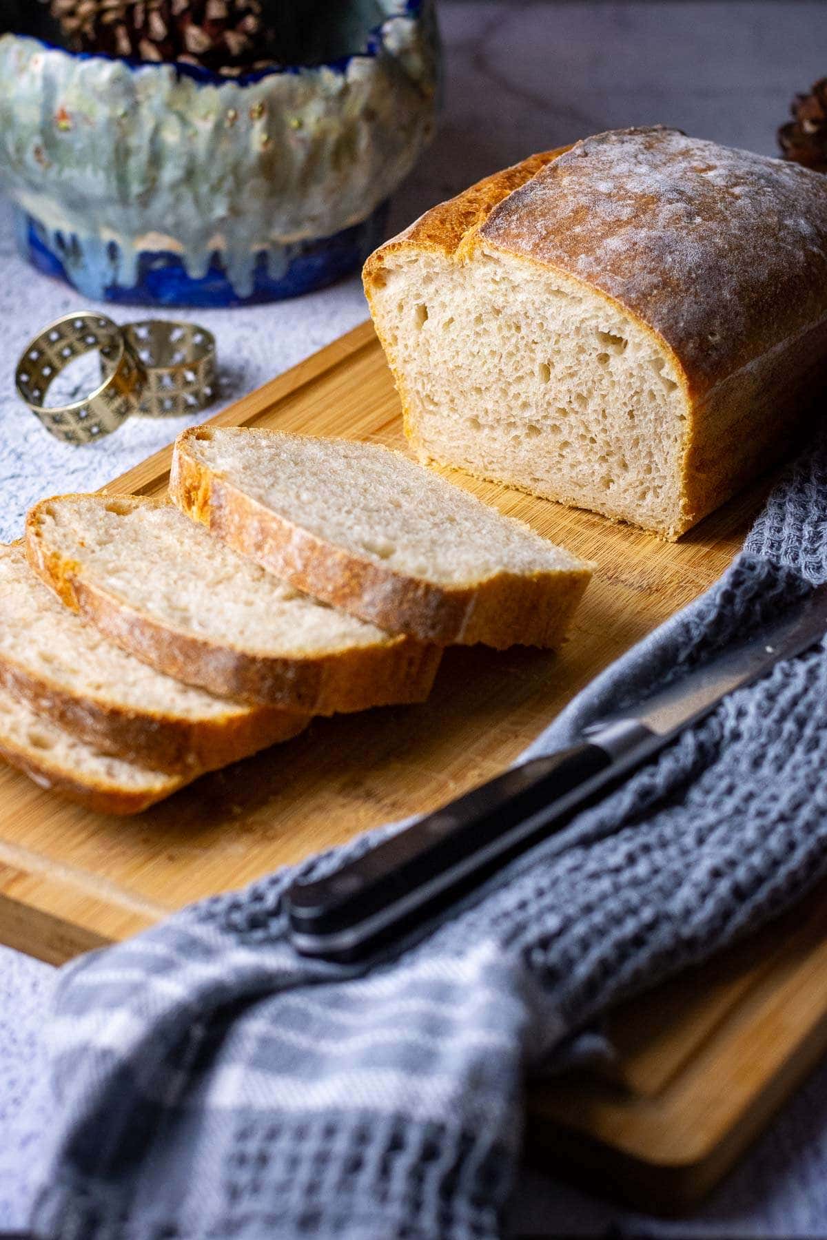 Sourdough baked in a loaf pan, sliced on a wooden board.