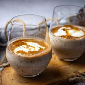 Two glasses with overnight cinnamon oats in topped with yogurt and extra cinnamon.