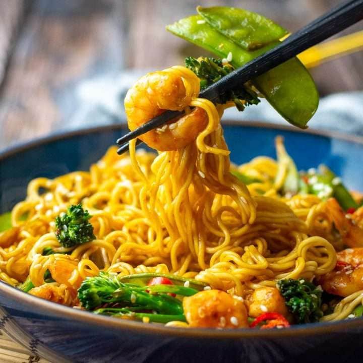 teriyaki Prawn and noodle stir fry being picked up with black chopsticks.