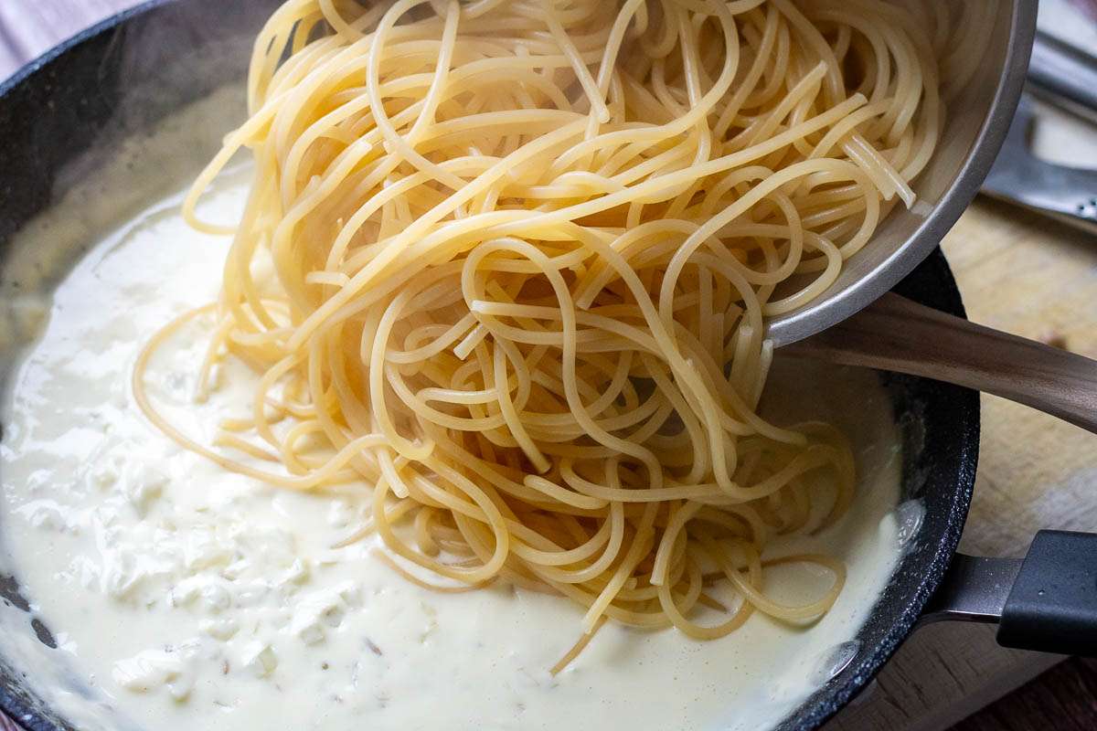 Cooked spaghetti added to creamy sauce.