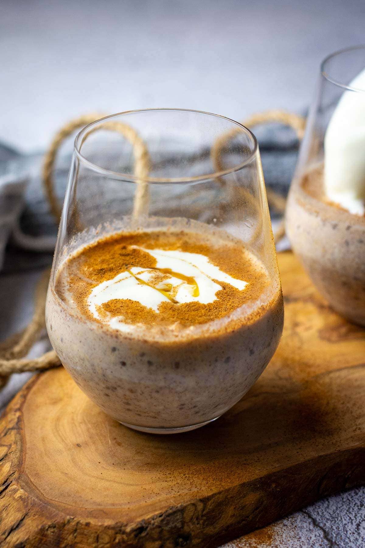Cinnamon oats in a glass set on a small wooden board.