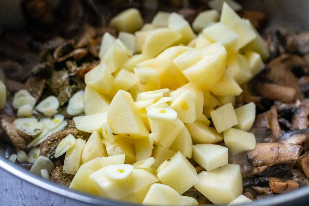 Potatoes and garlic added to mushroom pan.