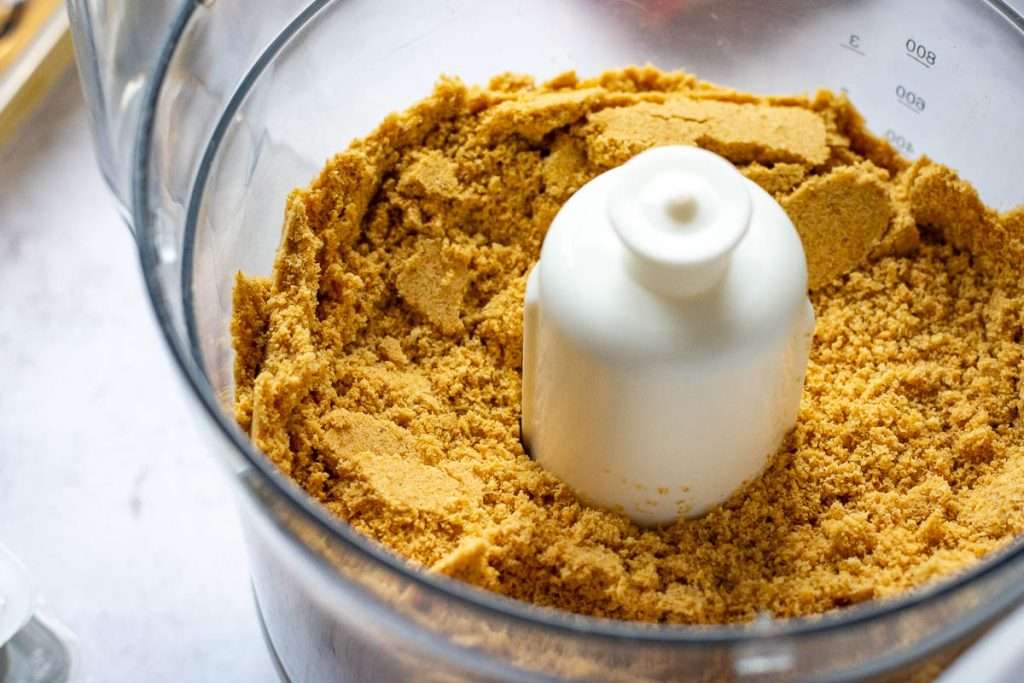 Digestive biscuits blitzed into crumbs in a food processor container.