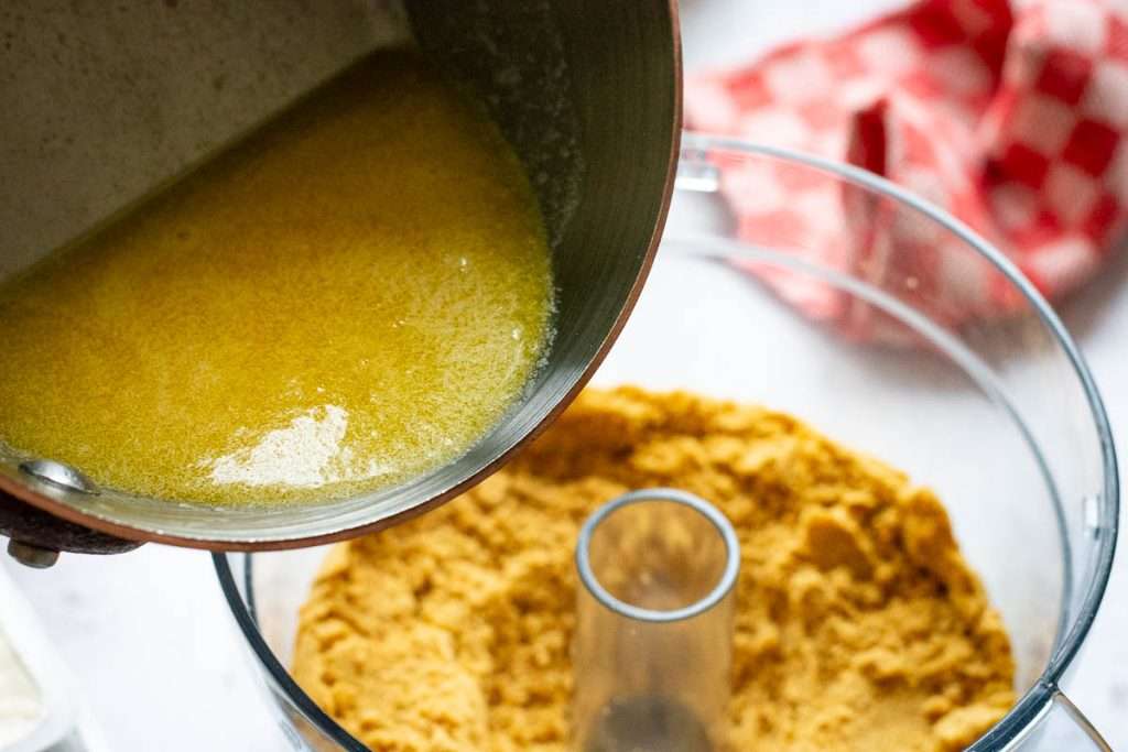 Pouring melted butter into the biscuit crumbs.