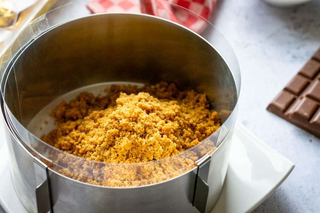 Butter and biscuit crumb mixture inside an acetate tape lined cake tin.