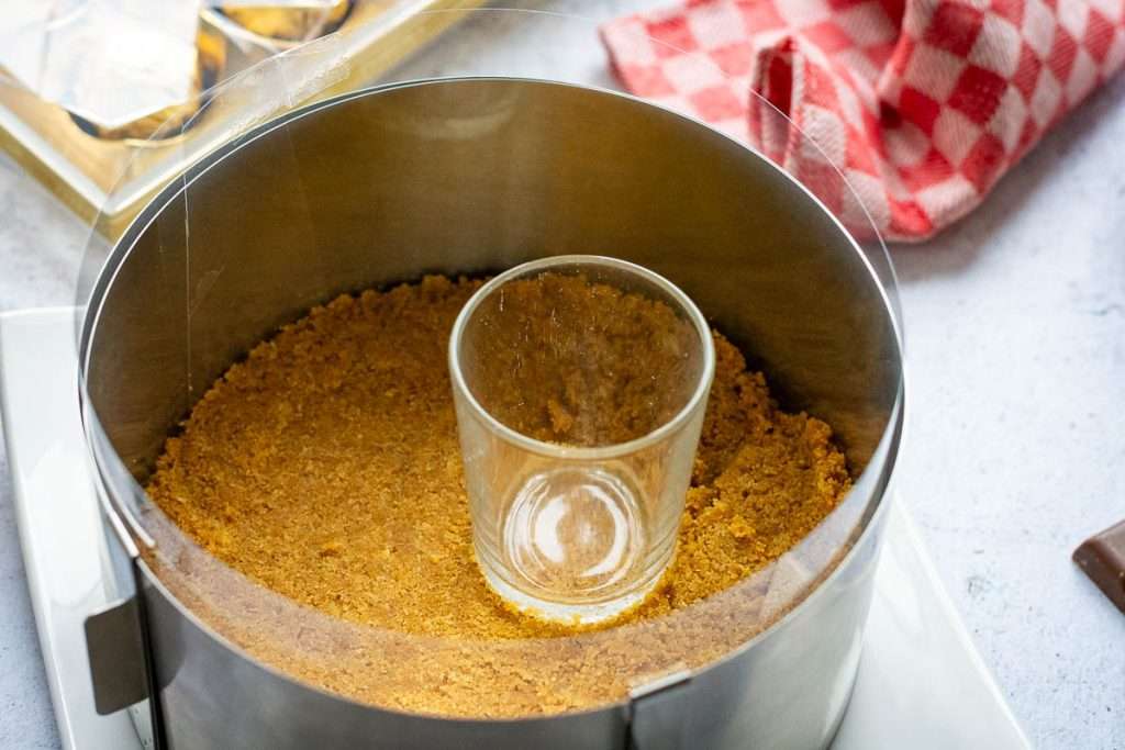 A small shot shot glass used to press the biscuit mixture into the base of the cake tin.