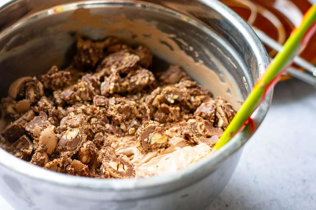 Roughly chopped ferrero rocher in a bowl with chocolate cheesecake mixture.