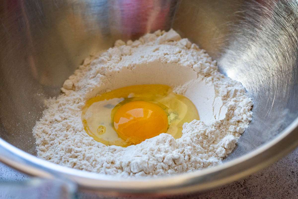 An egg cracked into the well in the flour.