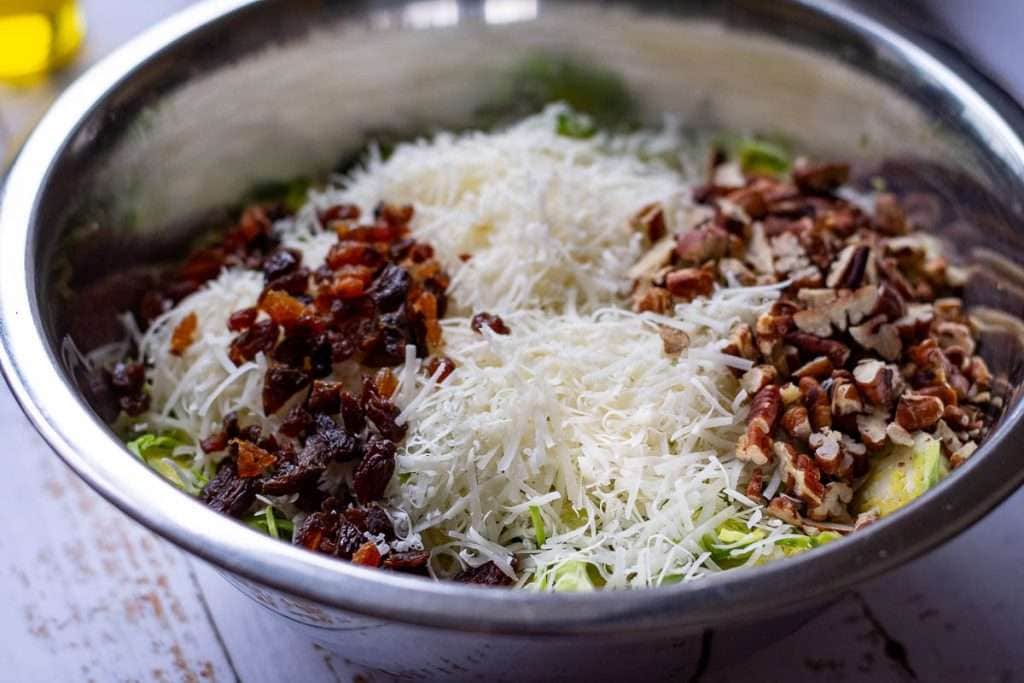 All Brussels sprout salad ingredients in a large metal bowl.