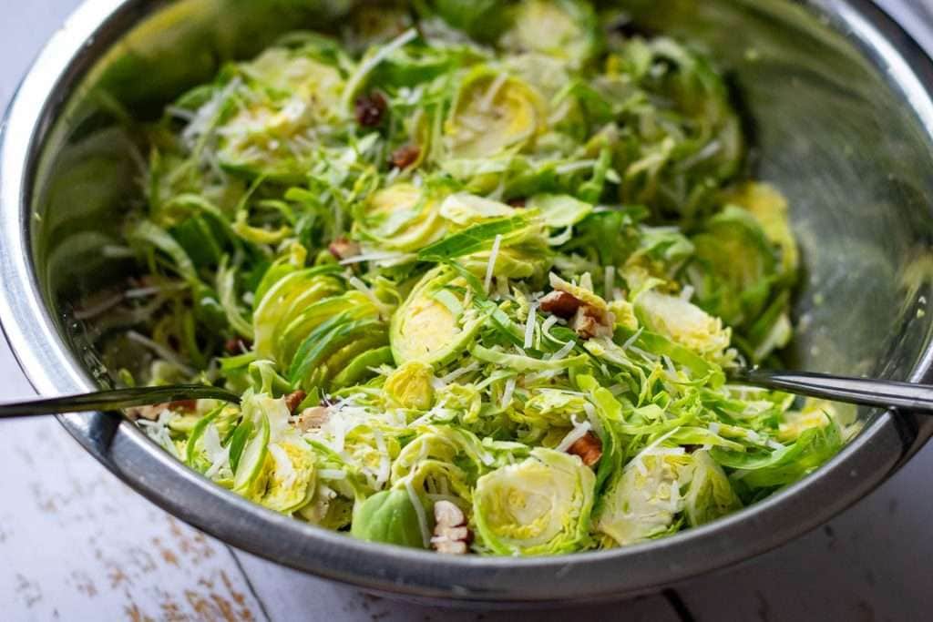 Parmesan Brussels Sprout Salad being tossed with the dressing.