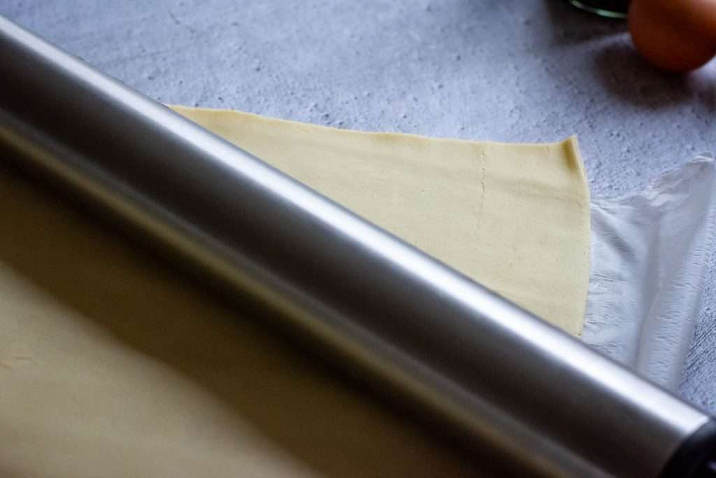 Rolling the ready-rolled shortcrust pastry a little wider to fit the dish using a stainless steel rolling pin.