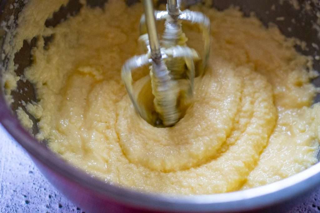 Beating the wet ingredients with a handheld electric whisk to make frangipane filling.