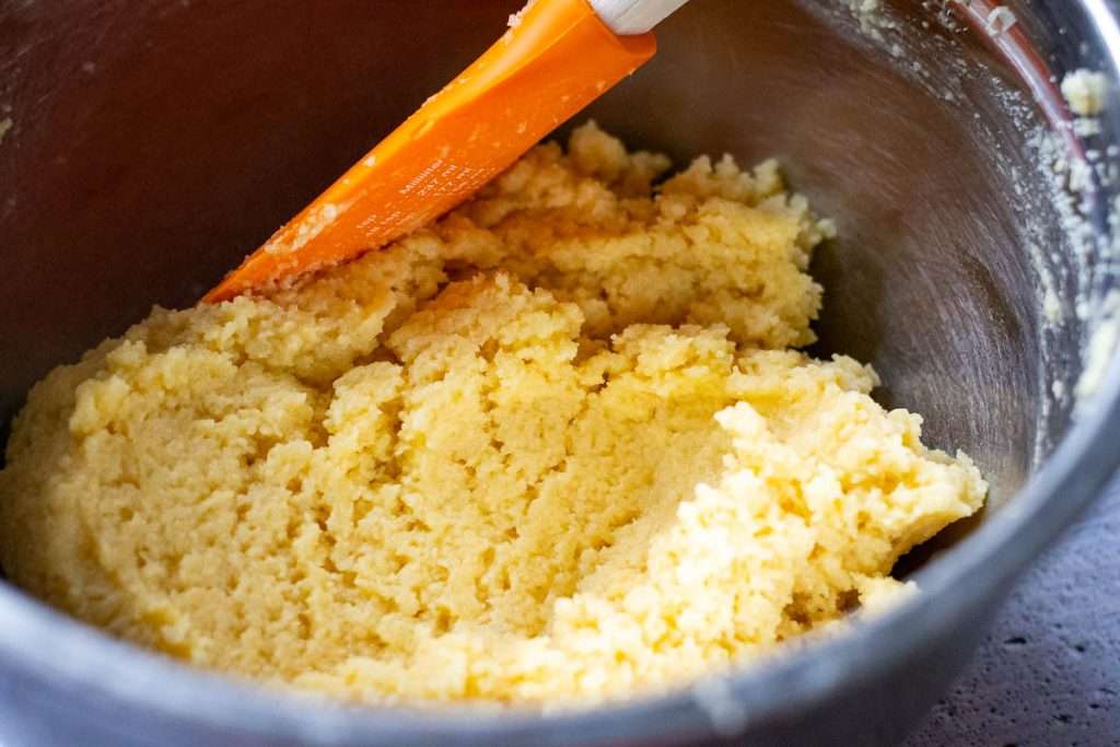 Folding ground almonds into the rest of the frangipane filling mxiture using an orange rubber spatula.