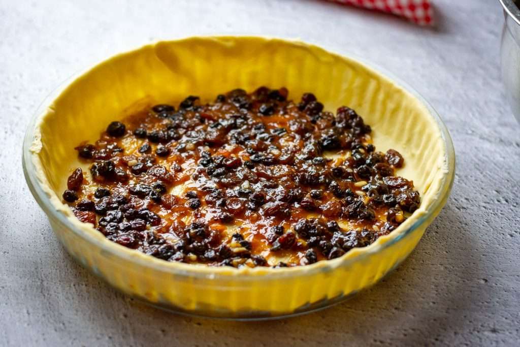 Mincemeat spread on the base of the shortcrust pastry.