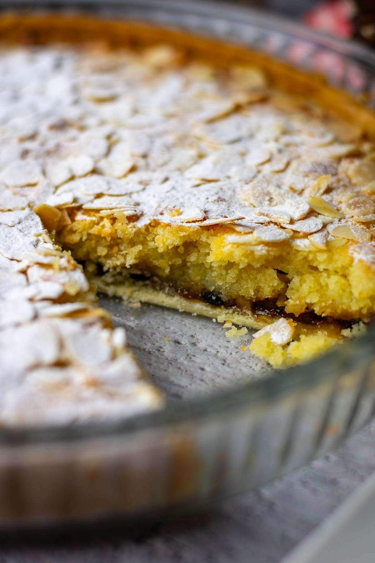 Bakewell tart with mincemeat with one slice missing in a glass dish.
