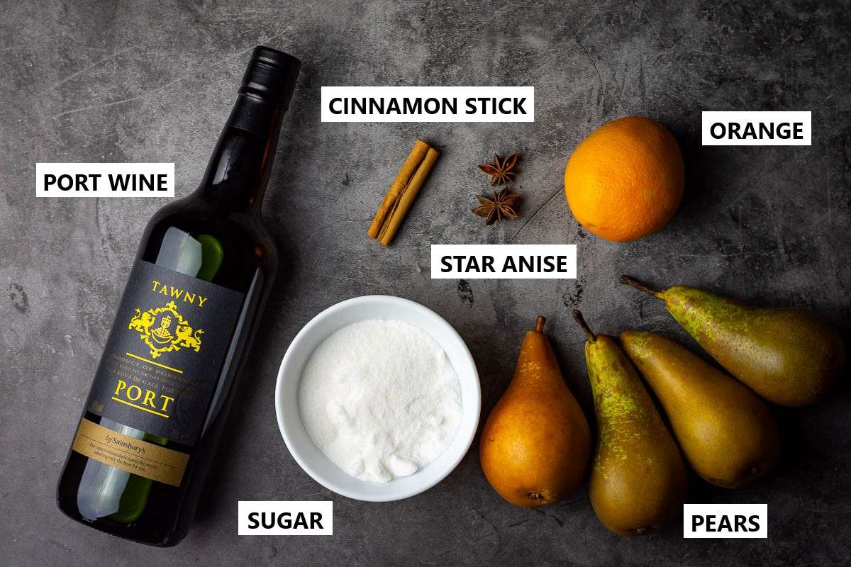 Ingredients for pears poached in port wine on a dark grey surface.