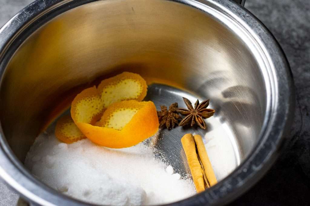 Cinnamon, star anise, orange peel and sugar in a pan.