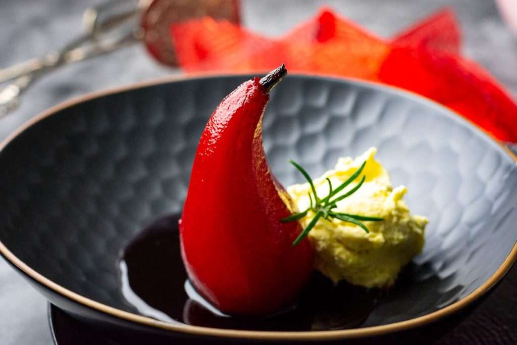 Poached pear in a pool oif port wine reduction with ice cream on the side.