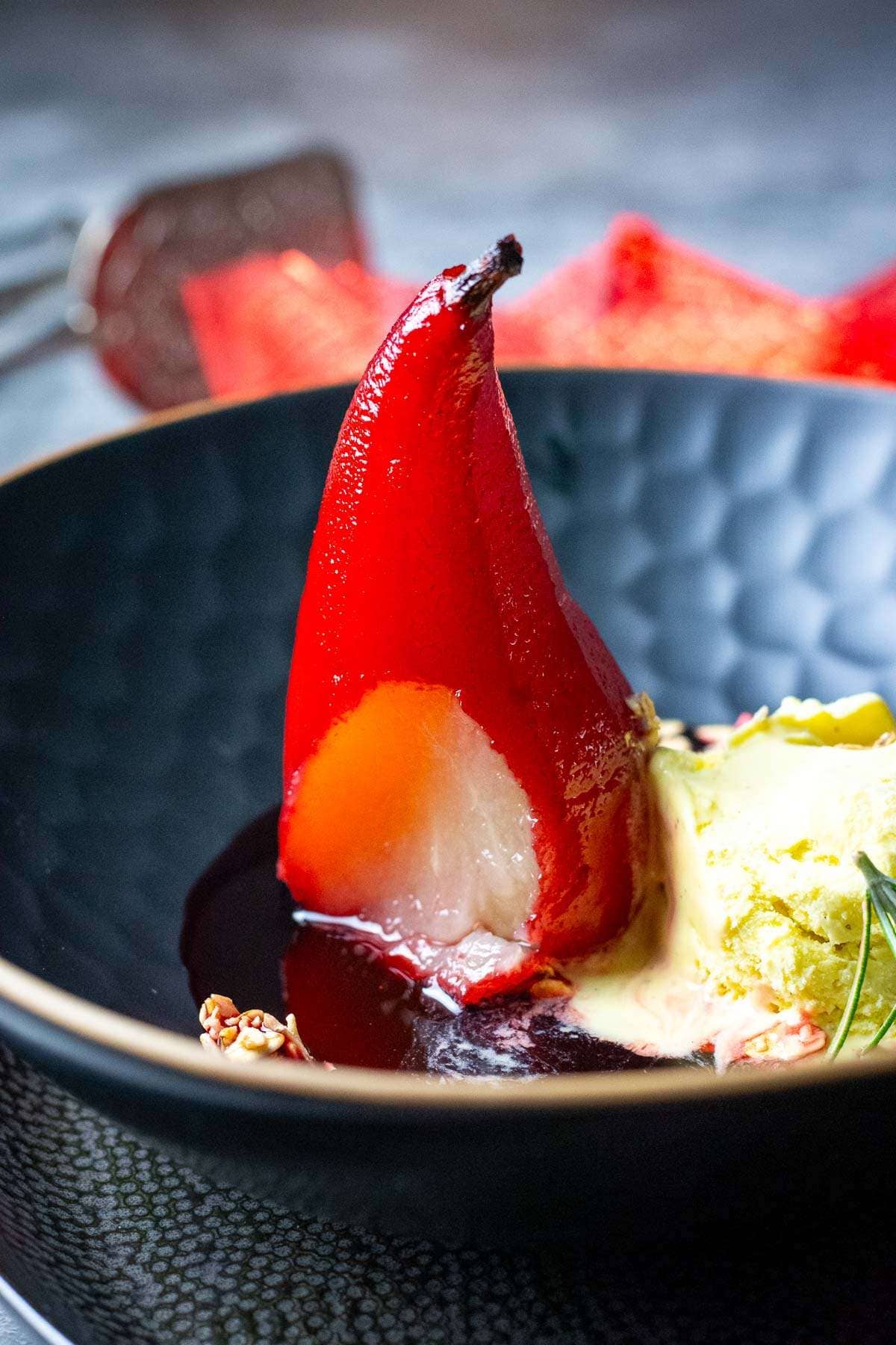 One spoonful cut off the port poached pear exposing light inside.