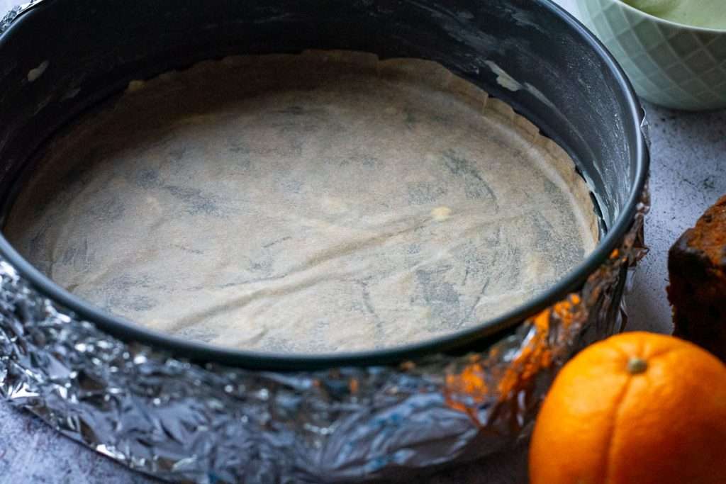 A springform cake tin wrapped in foil and lined with parchment paper.