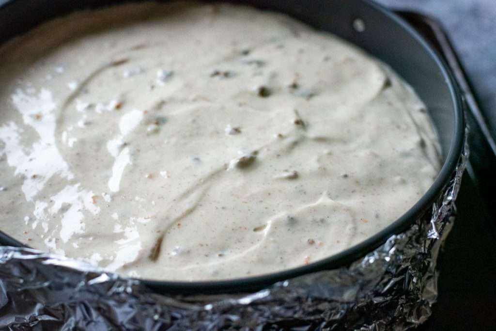 Cheesecake filling on top of the biscuit base ready for baking.