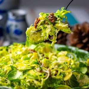 A portion of Parmesan Brussels Sprout Salad being picked up by a fork from a bowlful.