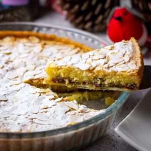 A slice of Christmas Bakewell Tart being cut.