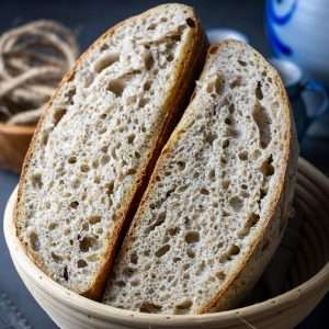 Flaxseed sourdough bread cut in half in a banetton basket.