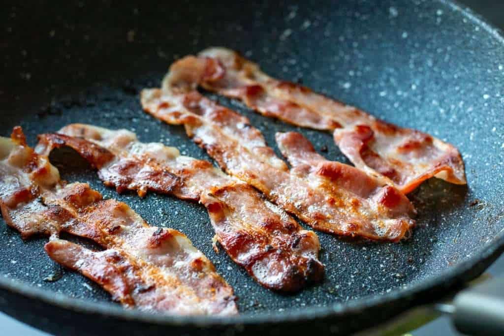 Browned and crispy bacon in a frying pan.