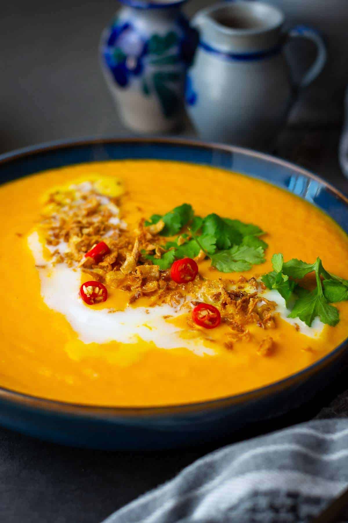 Carrit, Ginger and Coconut Soup garnished with a swirl of extra coconut milk, and garnished with crispy onions, coriander and chilli slices.