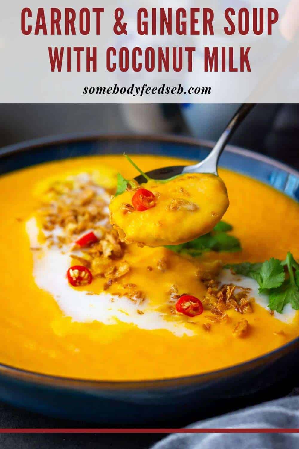 Carrot, ginger, and coconut milk soup with garnishes on top in a blue bowl - Pin for Pinterest.