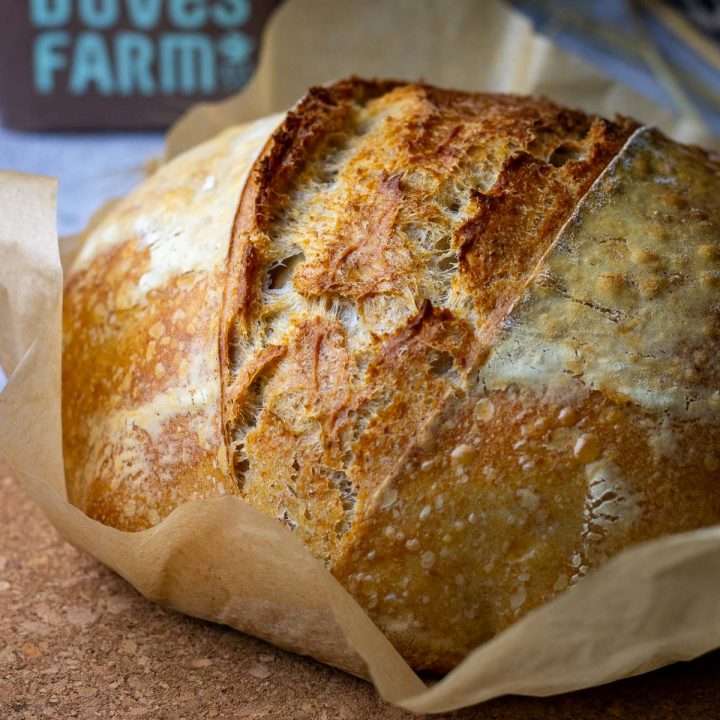 Spelt Sourdough Bread on a piece of parchment paper with expansion right in the middle.