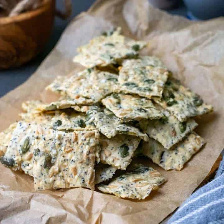 Seeded Sourdough Crackers made with sourdough discard on a sheet of parchment paper.
