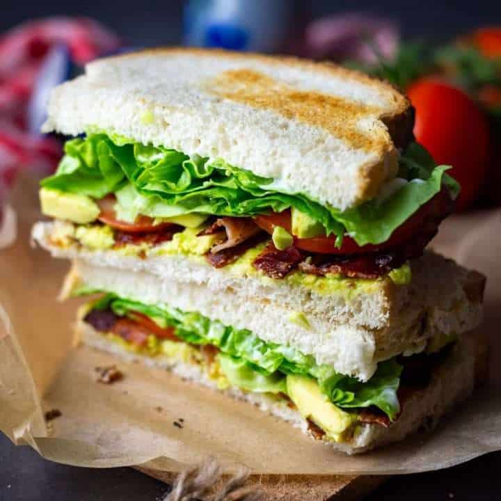 Two halves of BLTA sandwich on a piece of brown paper.