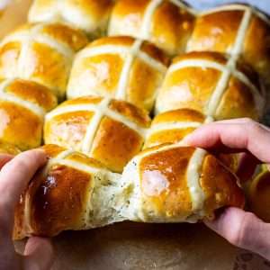 Lemon Poppy Seed Hot Cross Buns being torn apart by two hands.