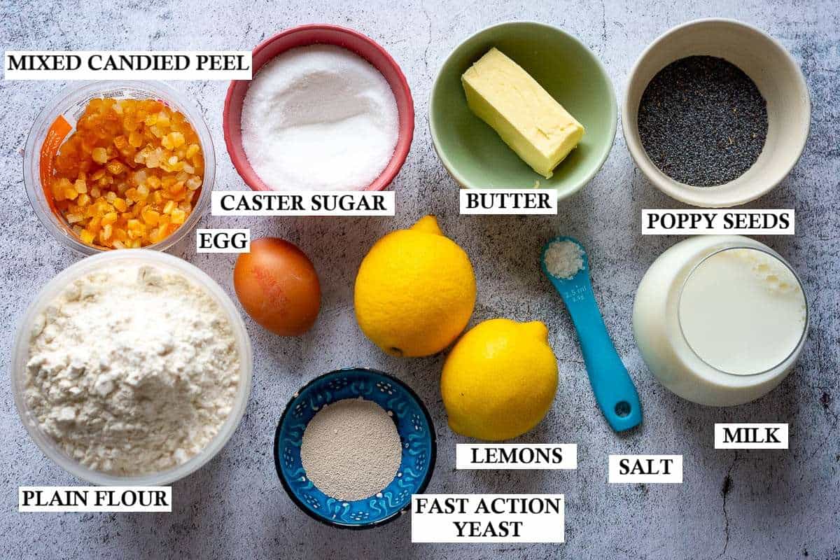 Ingredients for Lemon and poppy seed Easter buns on a light grey surface.