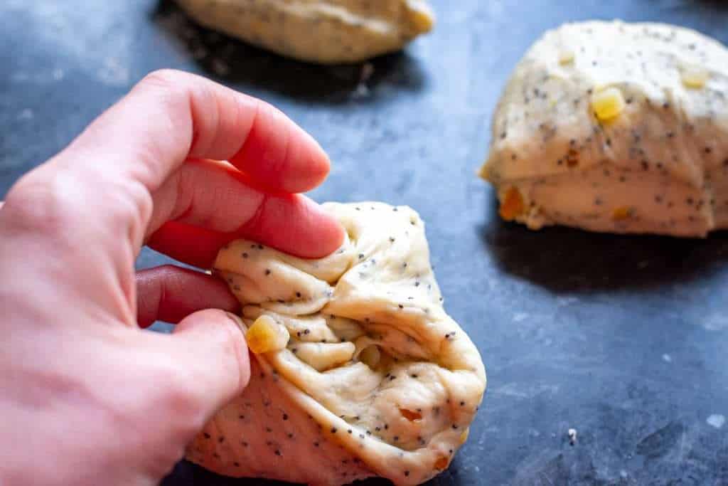 Shaping each piece of dough into the ball by folding the edges into the middle.