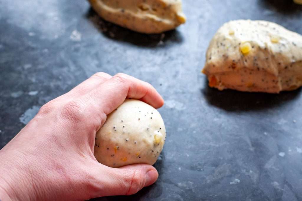 Rolling the ball of dough on the kitchen surface to create surface tention for a smooth ball of dough.