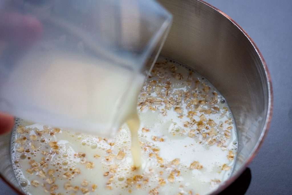Pouring mlk over the porridge oats in a small saucepan.