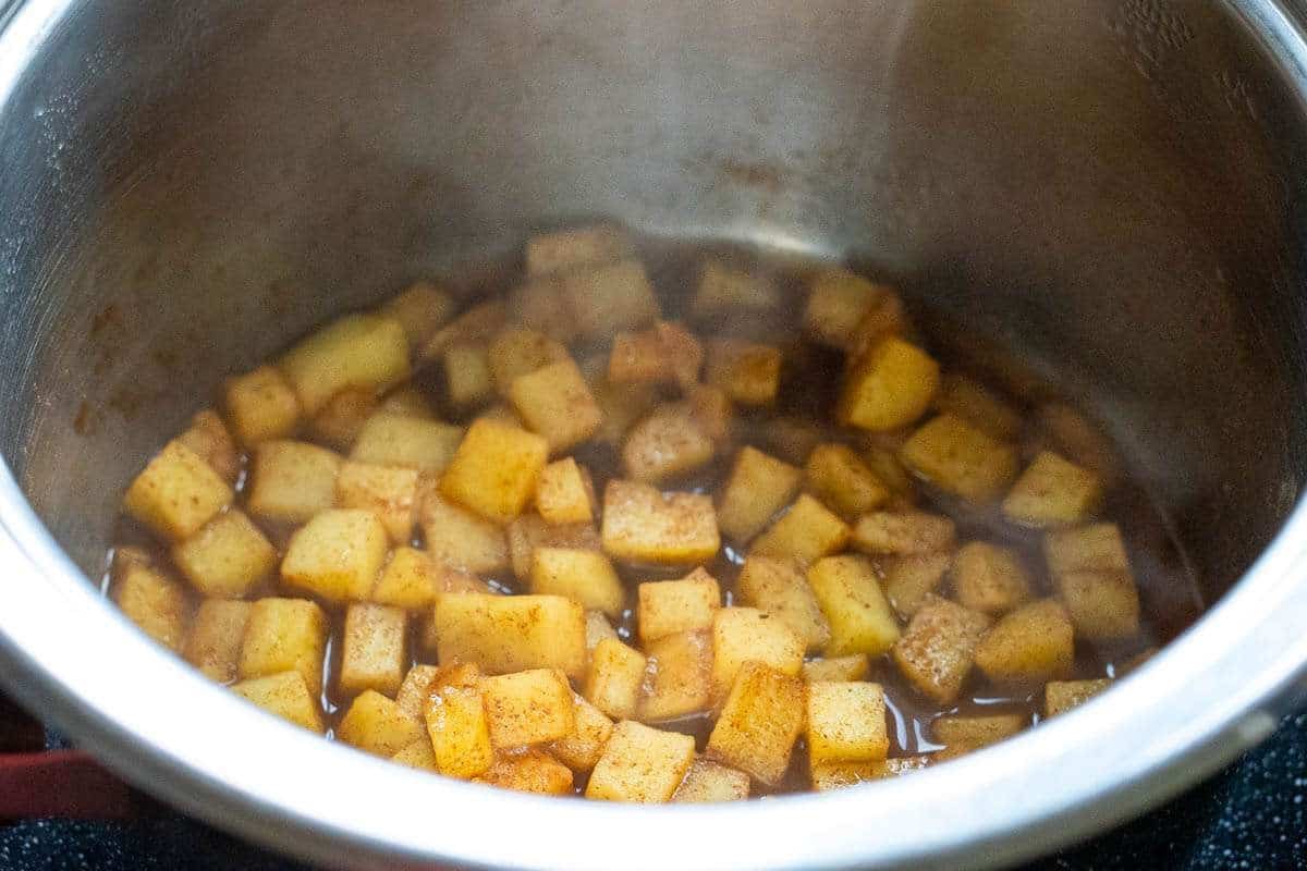 Apples and cinnamon stewing in a small saucepan.